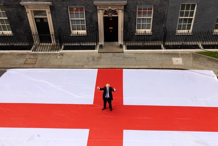 Prime Minster Boris Johnson poses with giant St George's Flag spread out on the road outside 10 Downing Street