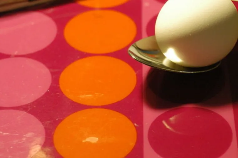 Egg on a spoon on a colourful tablecloth